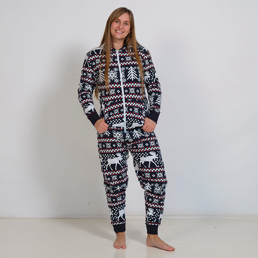 En kvinde poserer i et mønstre julejumpsuit.